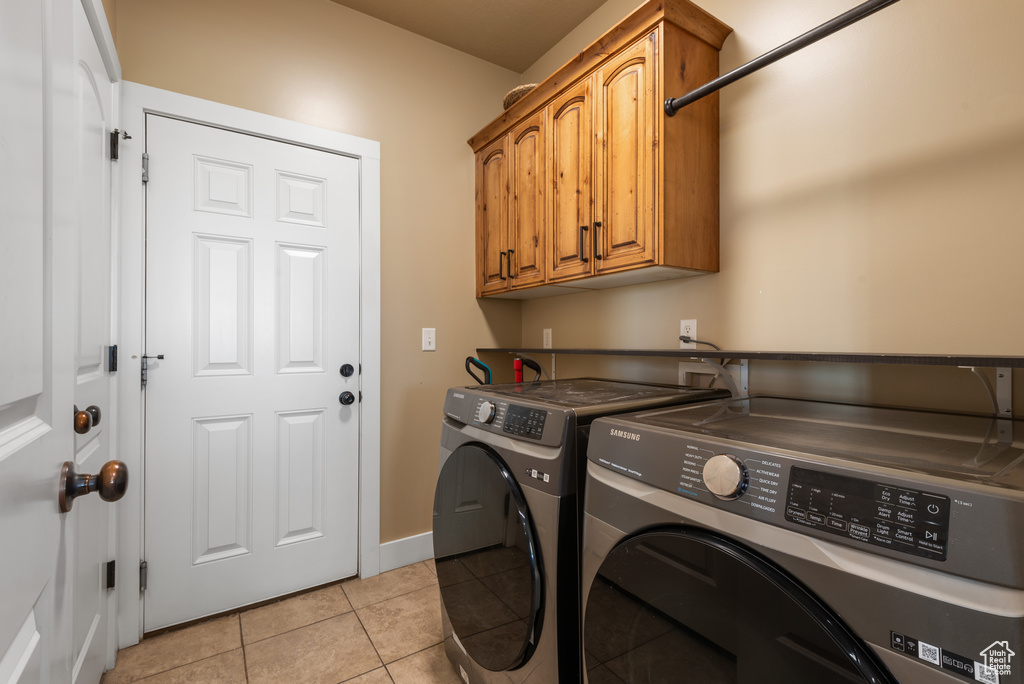 Laundry area featuring cabinet space, washer and dryer, and light tile patterned flooring