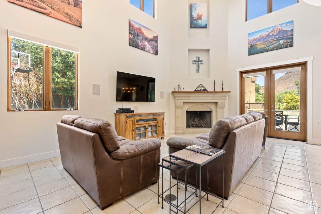 Living room featuring light tile patterned flooring, a high ceiling, a premium fireplace, and french doors