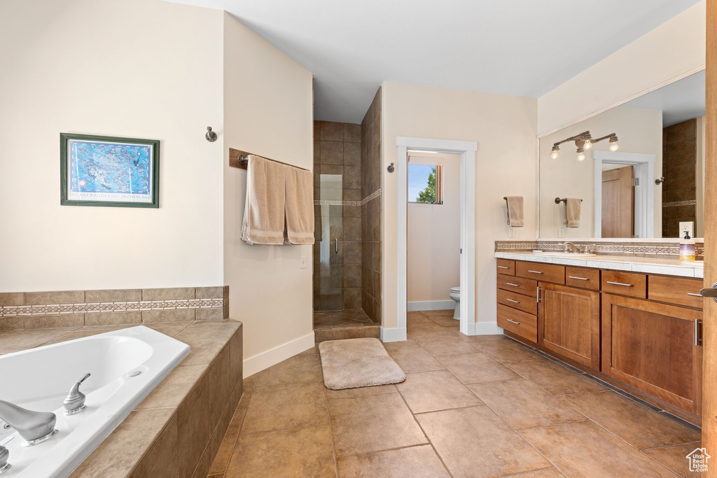 Bathroom featuring a garden tub, vanity, a shower stall, and tile patterned floors