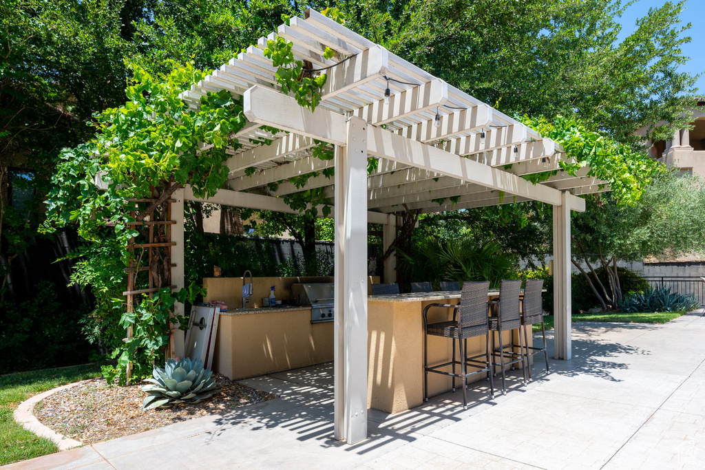 View of patio / terrace featuring a bar, a pergola, and exterior kitchen