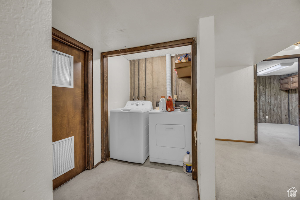 Laundry area with washing machine and dryer, carpet flooring, and wood walls