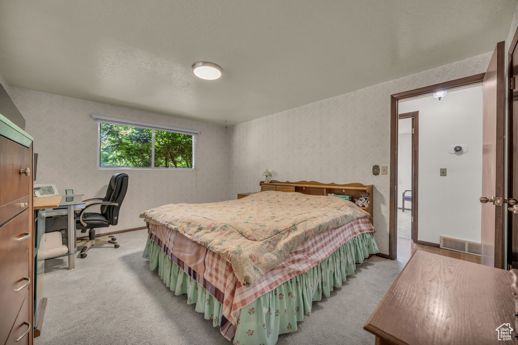 Bedroom with light carpet and an office area