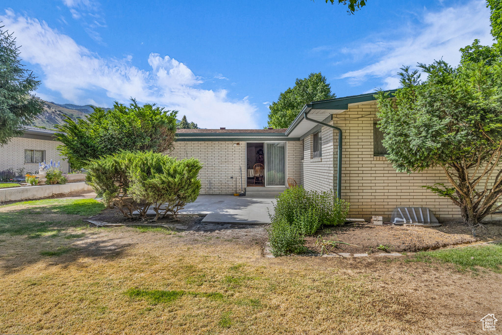 Back of property with a patio, a yard, and brick siding