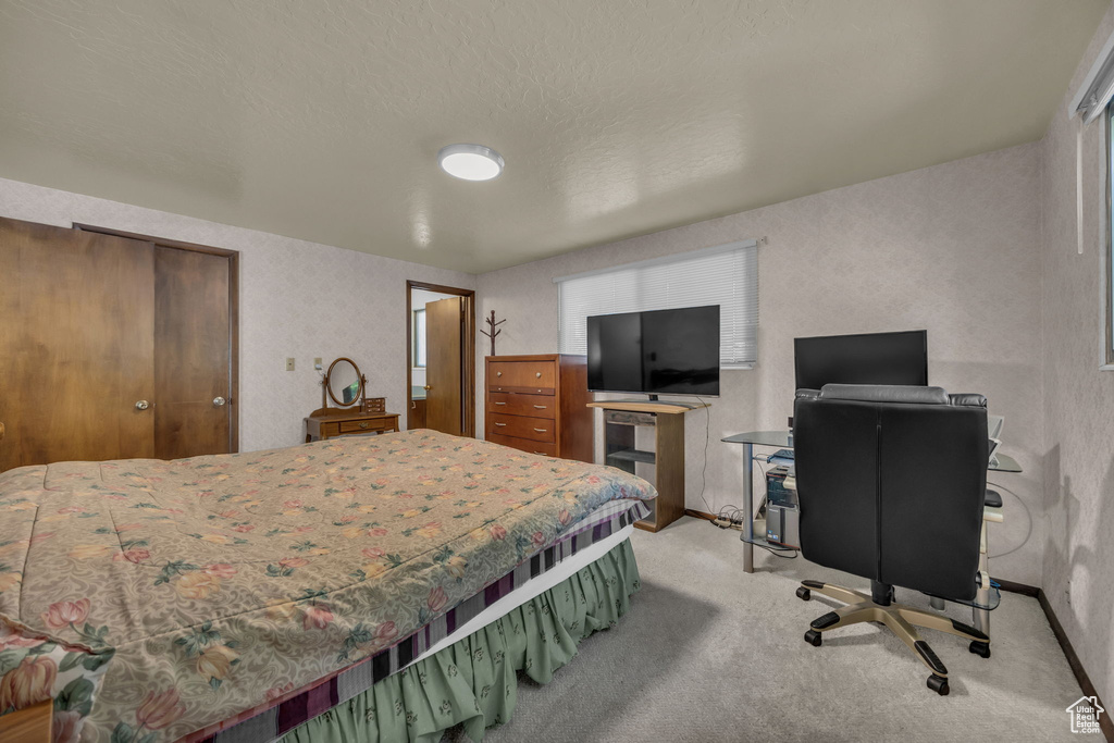Carpeted bedroom with baseboards and a desk