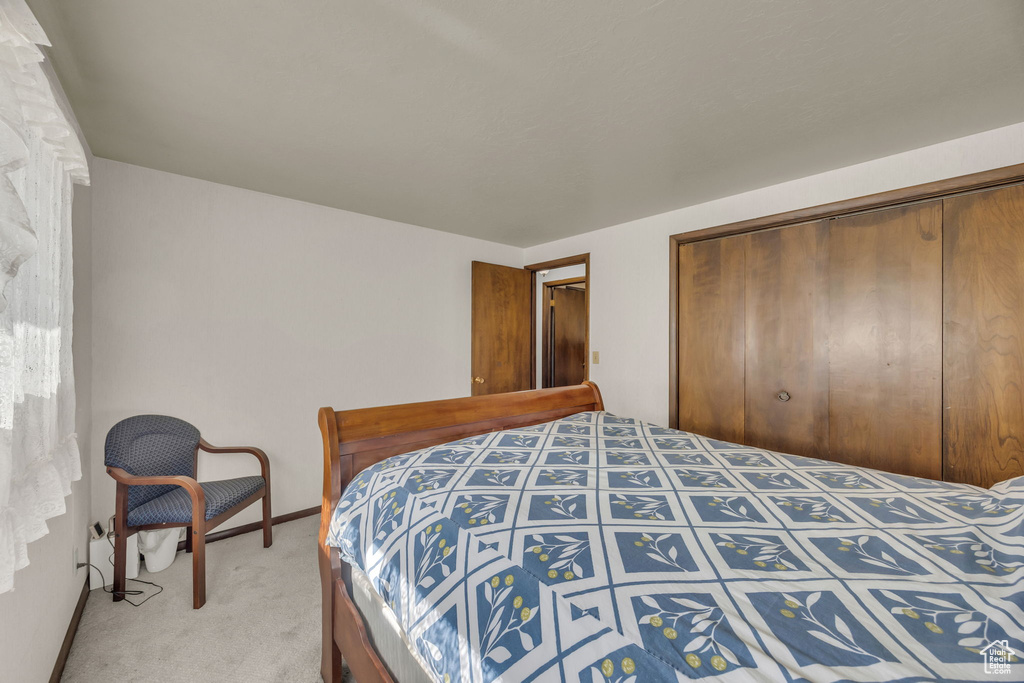 Bedroom with light carpet and a closet