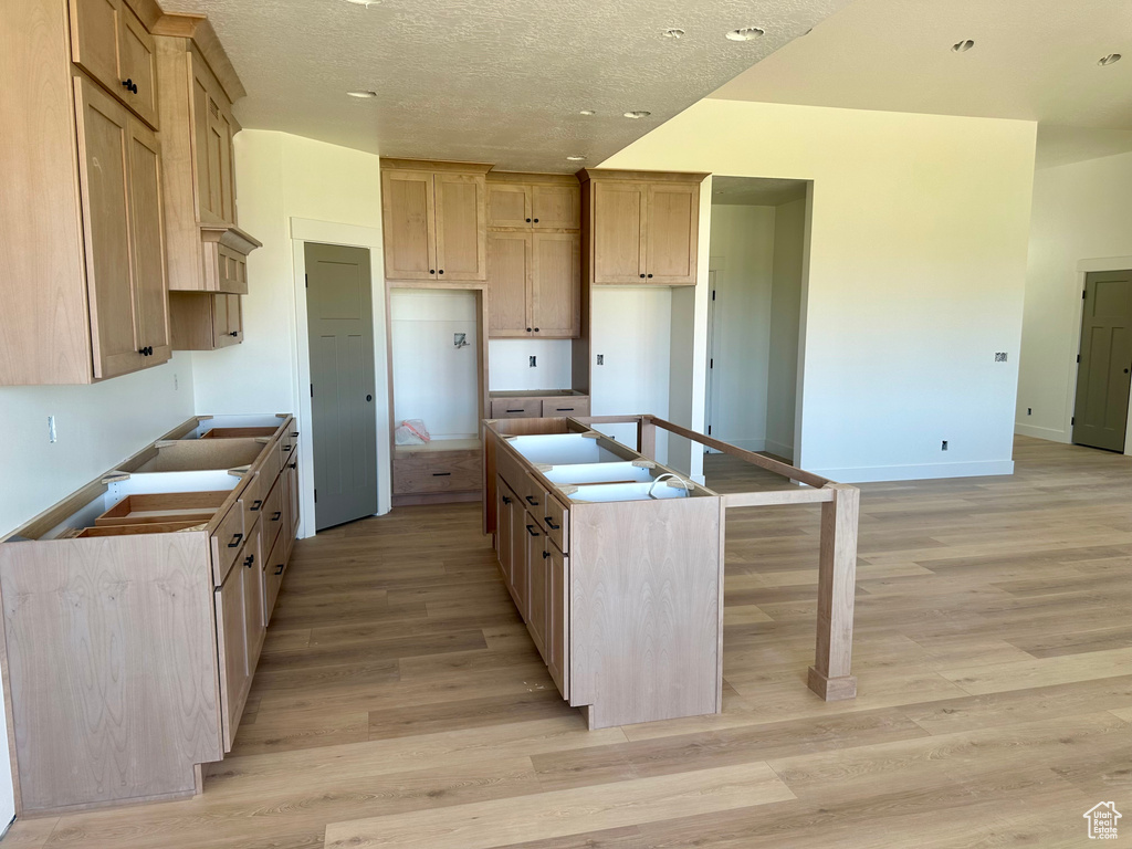 Kitchen with a center island with sink, light wood-style flooring, recessed lighting, and a textured ceiling