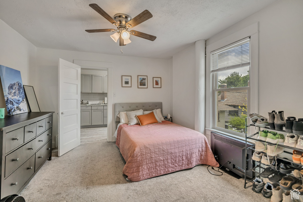 Bedroom with light colored carpet, ensuite bathroom, and a ceiling fan