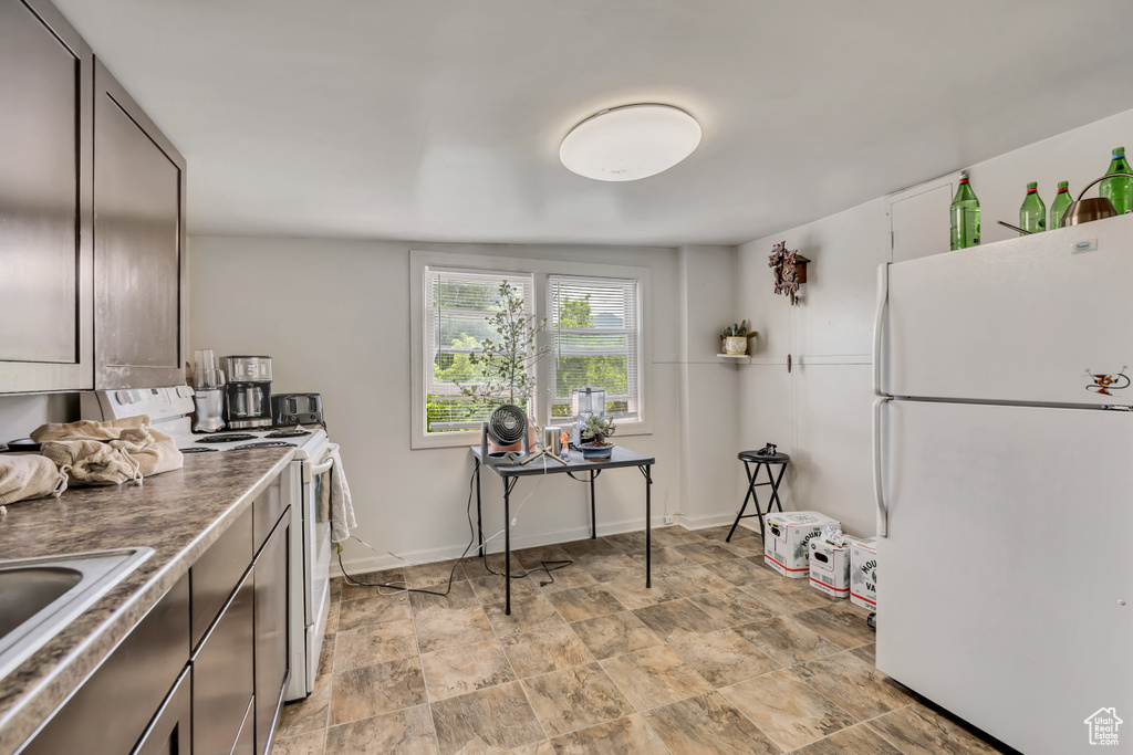 Kitchen featuring white appliances and stone finish floors
