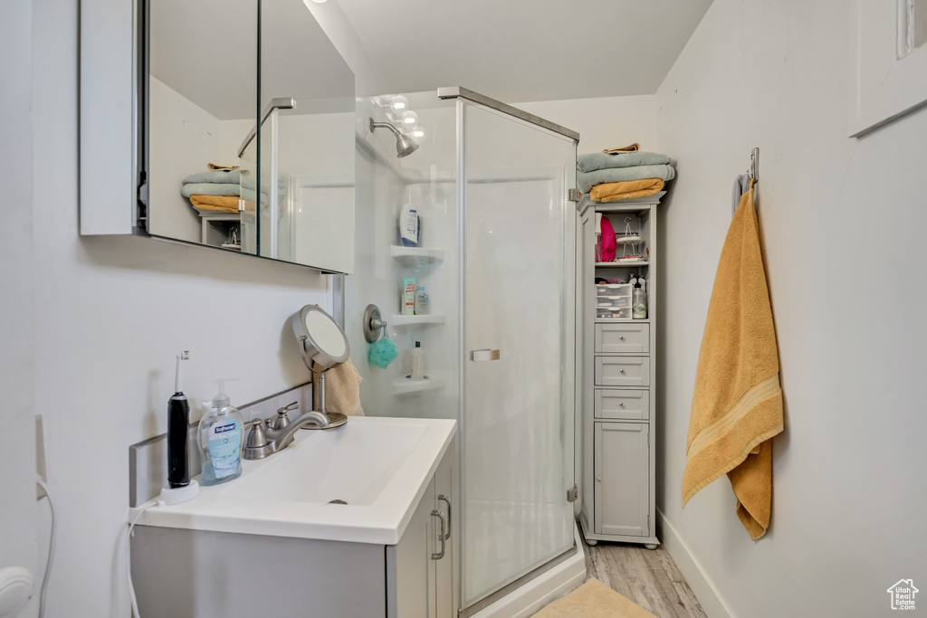 Bathroom with a stall shower, wood finished floors, and vanity