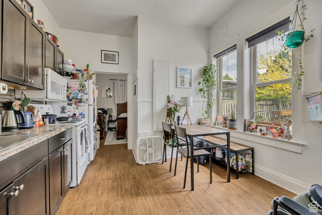 Kitchen featuring white appliances, dark brown cabinetry, and light wood-style floors