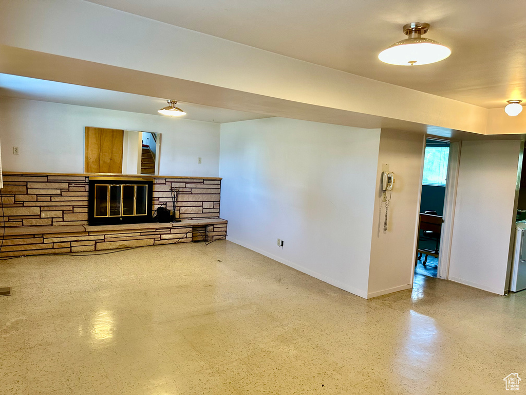 Unfurnished living room with a fireplace and baseboards