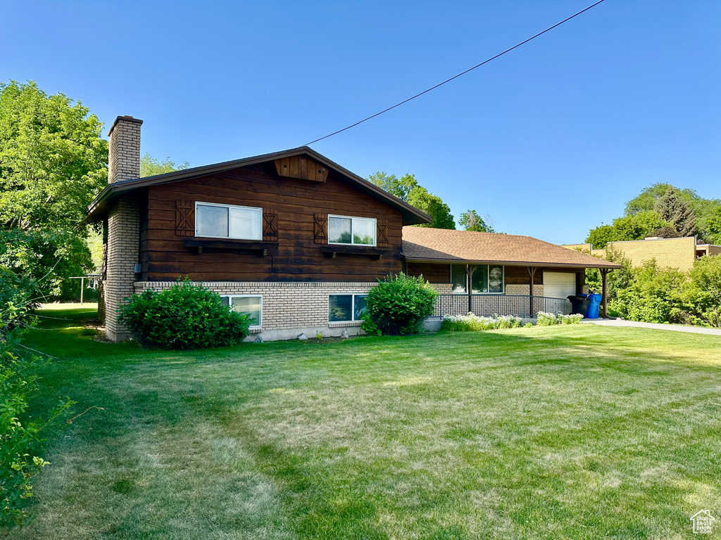 Rear view of house with a chimney, a yard, brick siding, and a garage