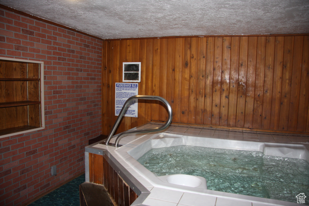 Detailed view of brick wall, a textured ceiling, wood walls, and a hot tub