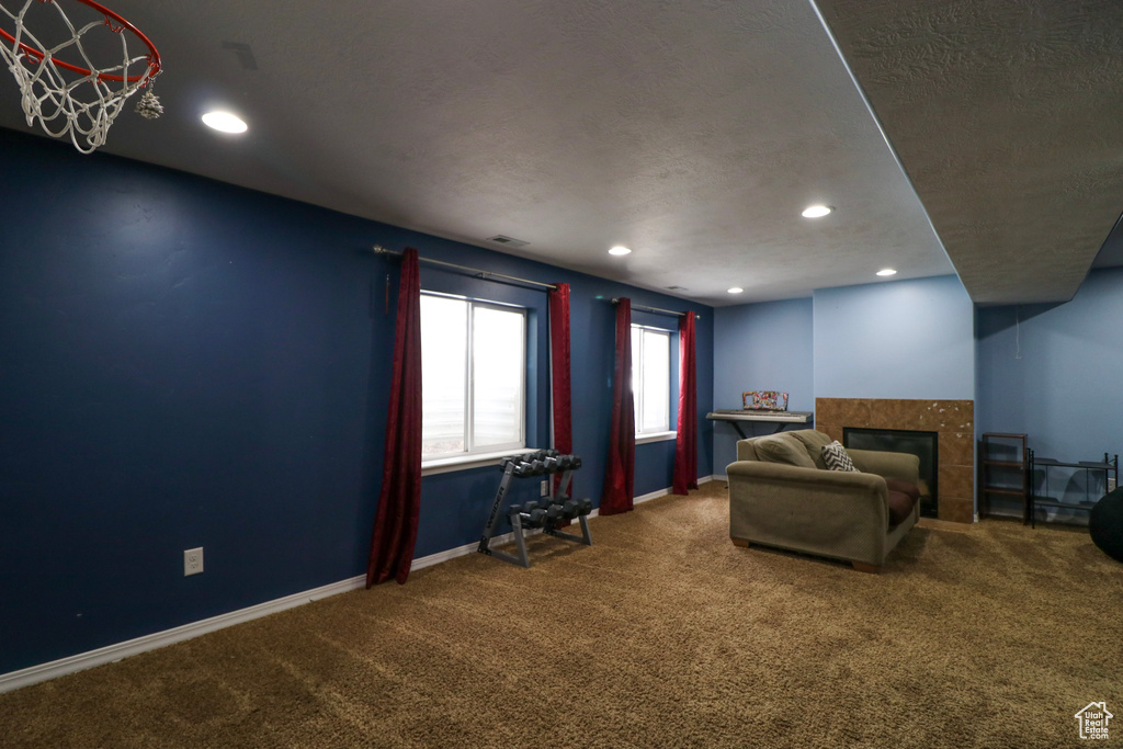 Carpeted living room with a tiled fireplace, recessed lighting, and a textured ceiling