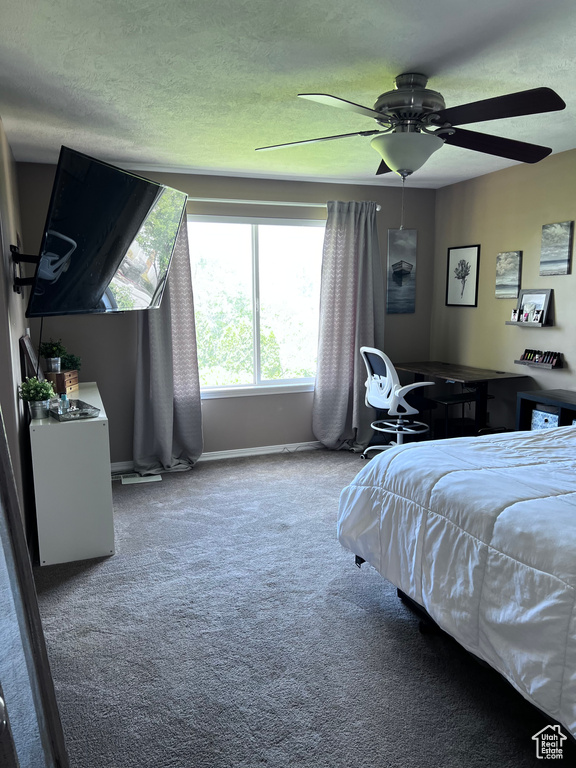 Carpeted bedroom featuring a ceiling fan and a textured ceiling