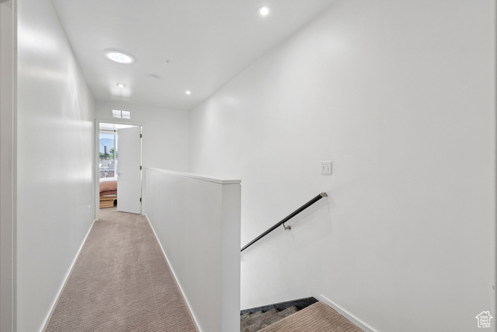 Hall with an upstairs landing, light colored carpet, and recessed lighting