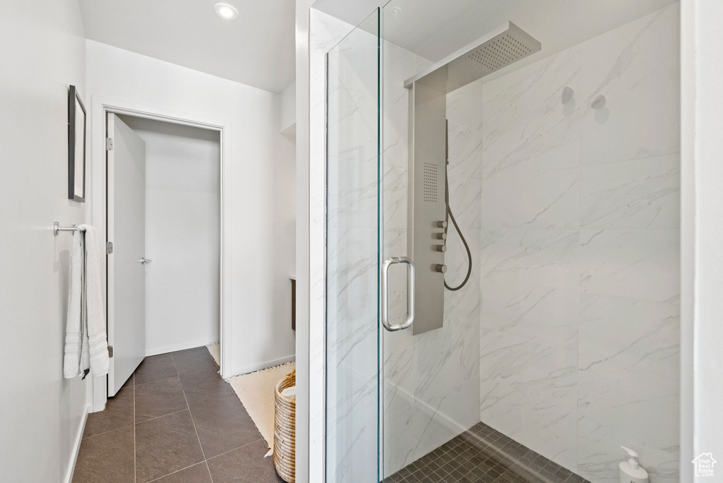 Full bathroom featuring a marble finish shower and tile patterned flooring