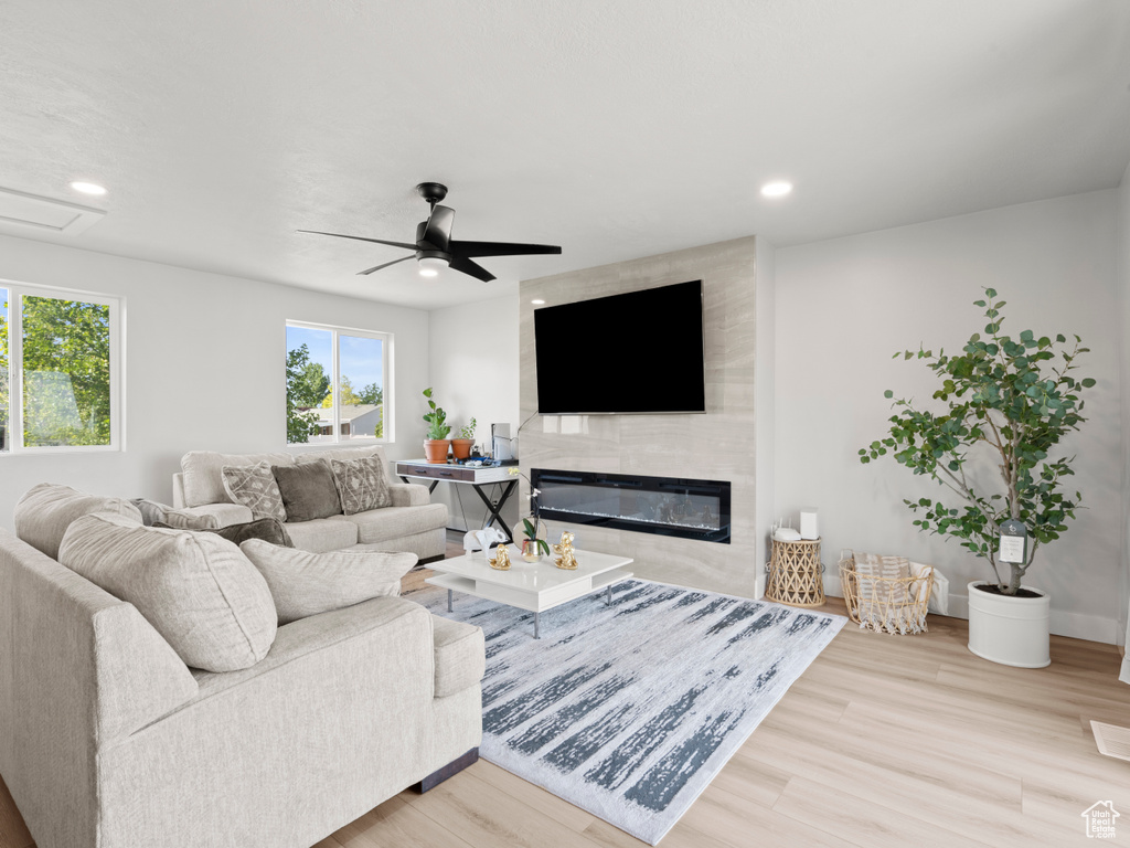 Living room featuring wood finished floors, a ceiling fan, recessed lighting, and a large fireplace