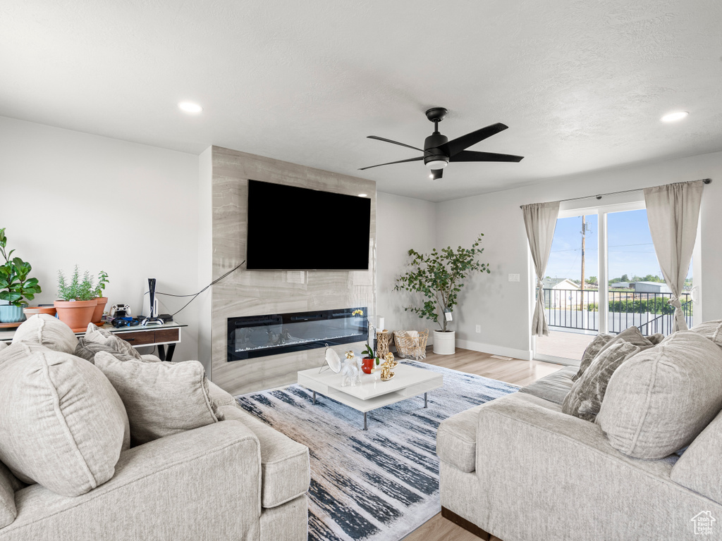 Living room featuring wood finished floors, a fireplace, a ceiling fan, and recessed lighting