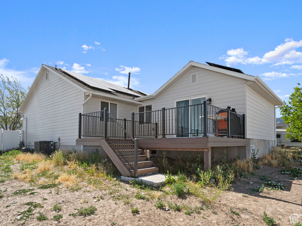 Back of property with solar panels, a deck, and stairway