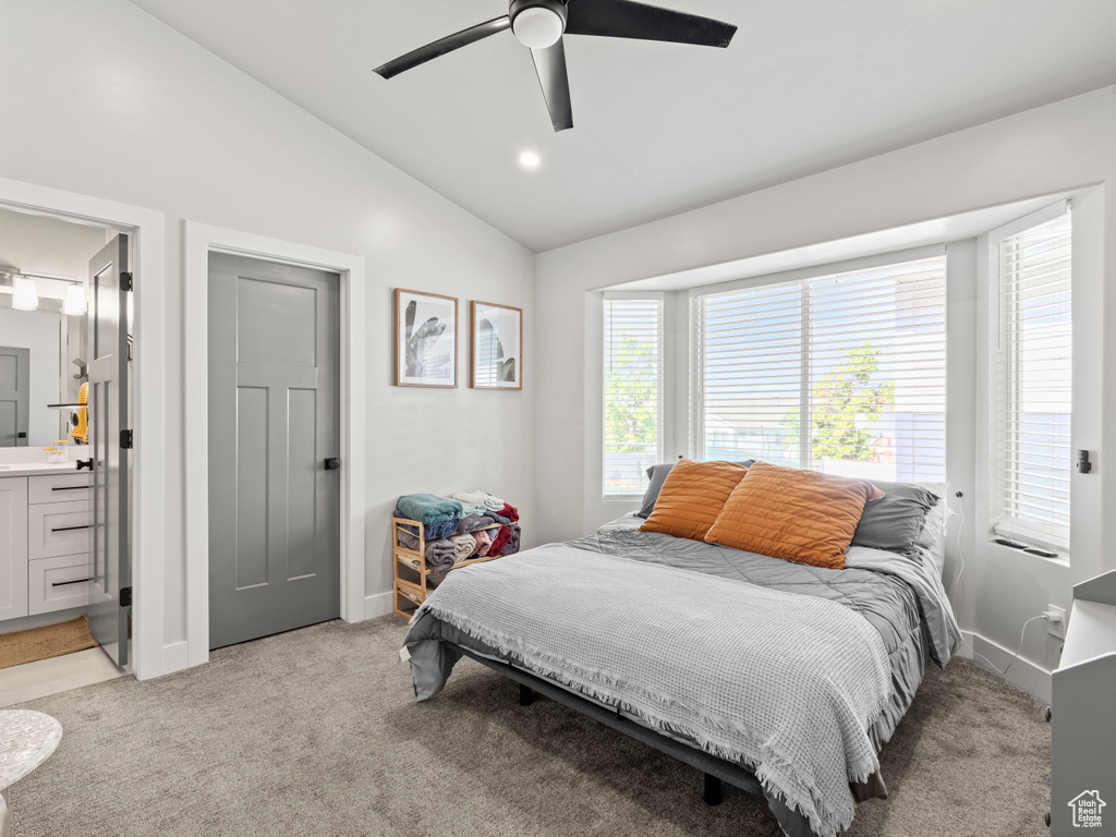 Bedroom featuring light colored carpet, vaulted ceiling, ensuite bathroom, and ceiling fan