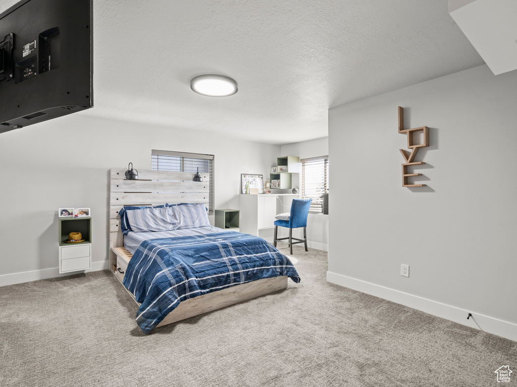 Carpeted bedroom featuring baseboards and a textured ceiling