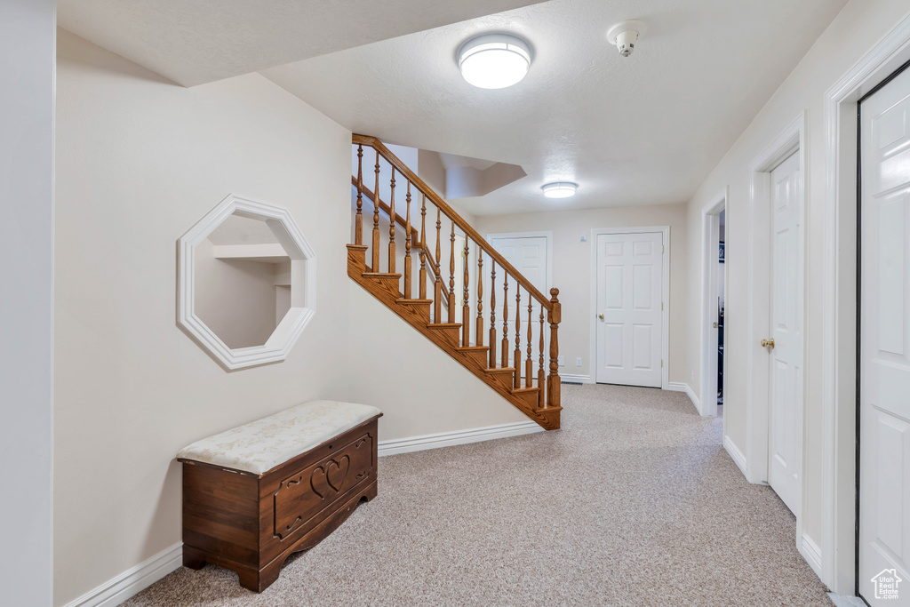 Carpeted entrance foyer featuring stairway and baseboards