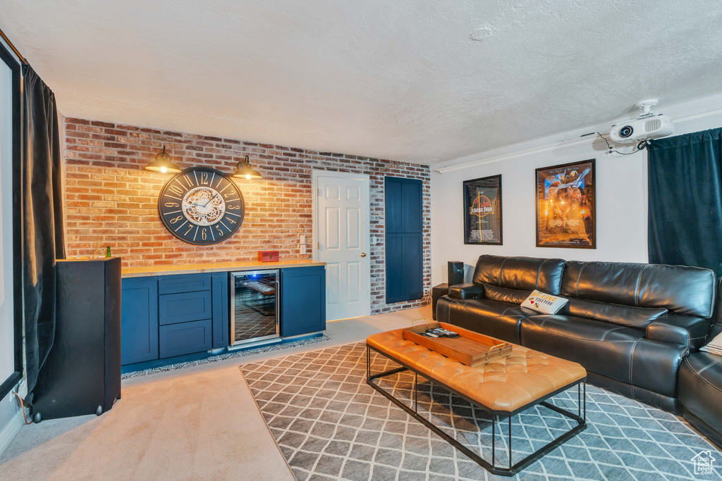 Living room featuring wine cooler, brick wall, a textured ceiling, and light colored carpet