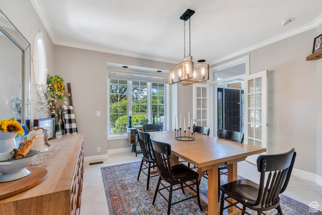 Dining room with a chandelier, crown molding, and french doors