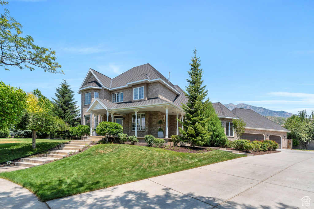 View of front of house featuring a garage, a front lawn, covered porch, driveway, and a standing seam roof