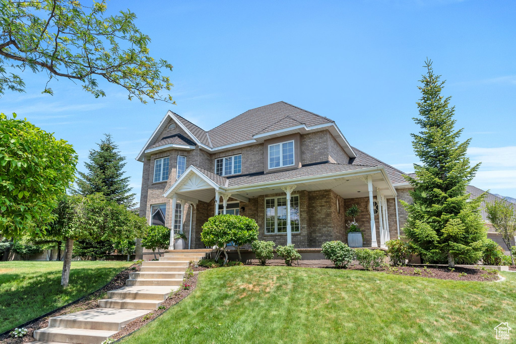 View of front of home with a front yard, brick siding, and covered porch