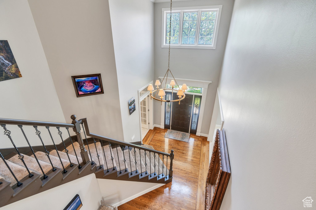 Foyer featuring a chandelier, healthy amount of natural light, wood finished floors, stairway, and a high ceiling