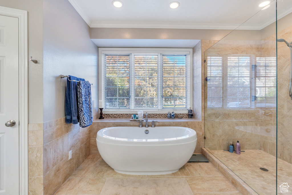 Full bathroom with a freestanding tub, tile walls, a tile shower, ornamental molding, and recessed lighting