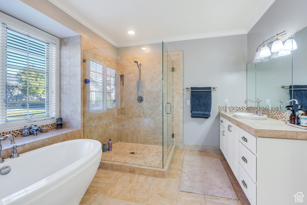 Full bathroom featuring a tub to relax in, crown molding, vanity, a stall shower, and tile patterned flooring