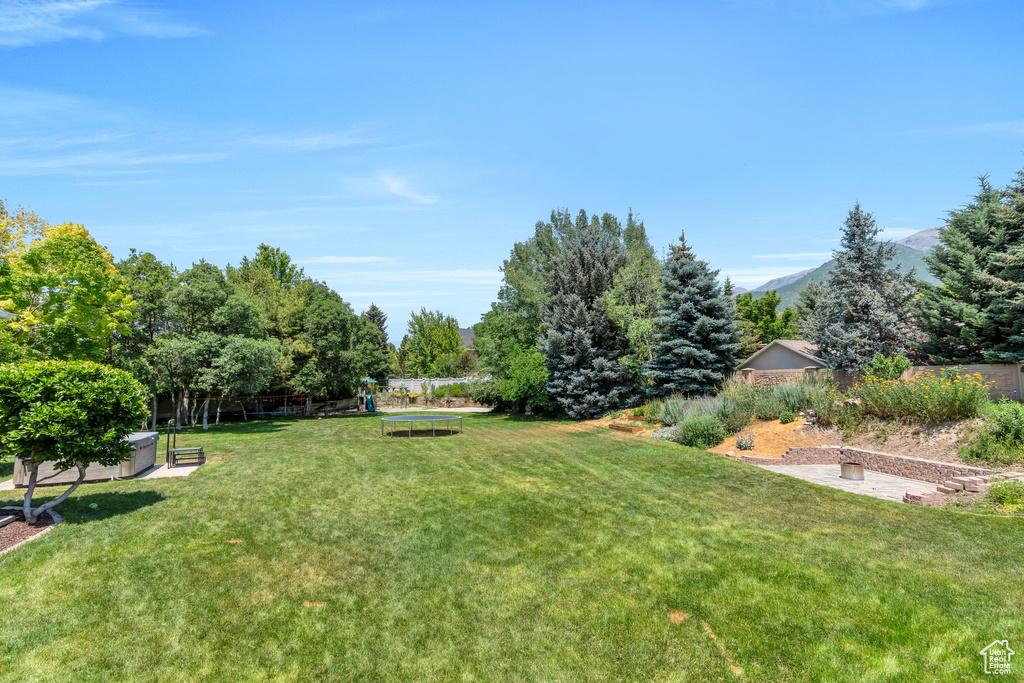 View of yard featuring a trampoline, a playground, and a mountain view