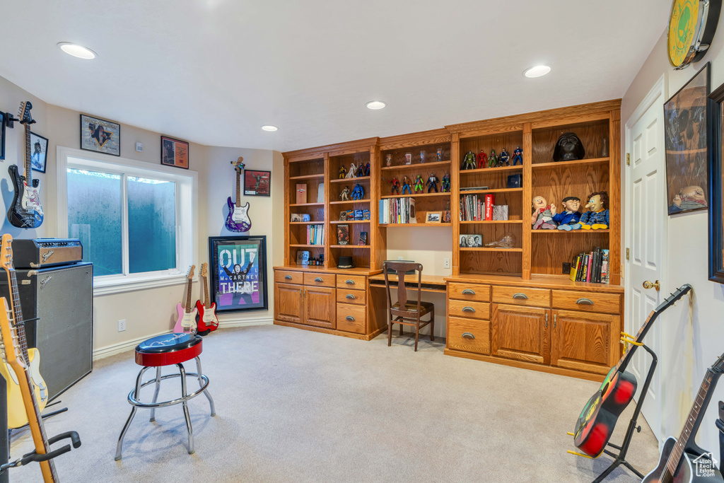 Office area with built in desk, recessed lighting, and light colored carpet