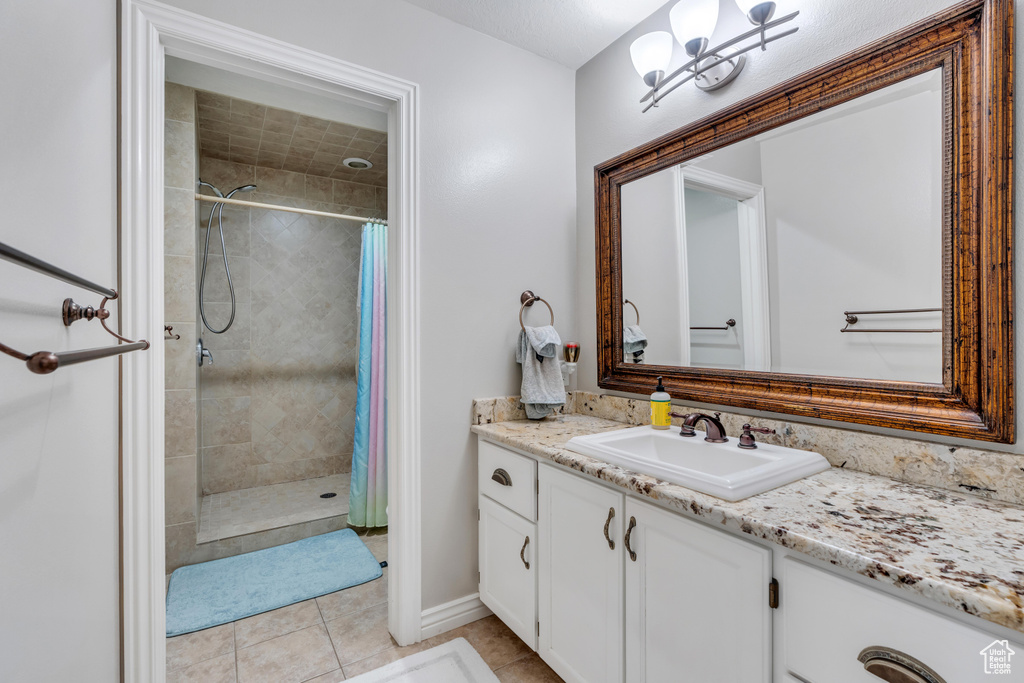 Full bathroom featuring vanity, a tile shower, tile patterned floors, and a chandelier