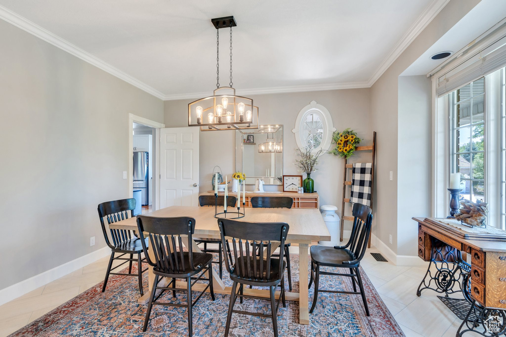 Dining space with plenty of natural light, a chandelier, ornamental molding, and light tile patterned floors