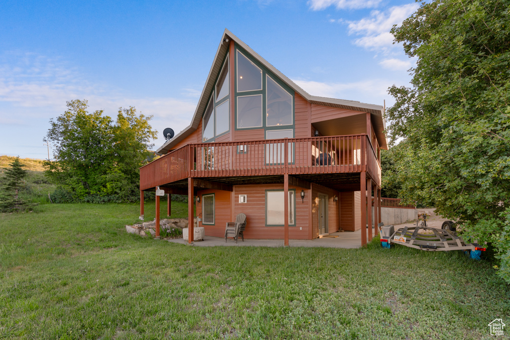 Rear view of property featuring a patio, a yard, and a wooden deck