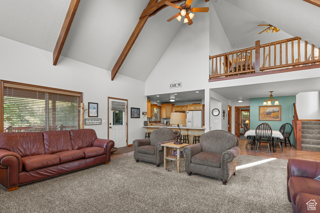 Carpeted living room featuring ceiling fan, high vaulted ceiling, stairs, and beamed ceiling
