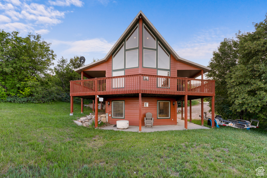Back of house featuring a patio, a lawn, and a wooden deck