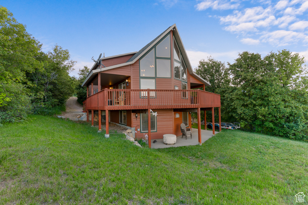 Back of property featuring a patio, a yard, and a wooden deck
