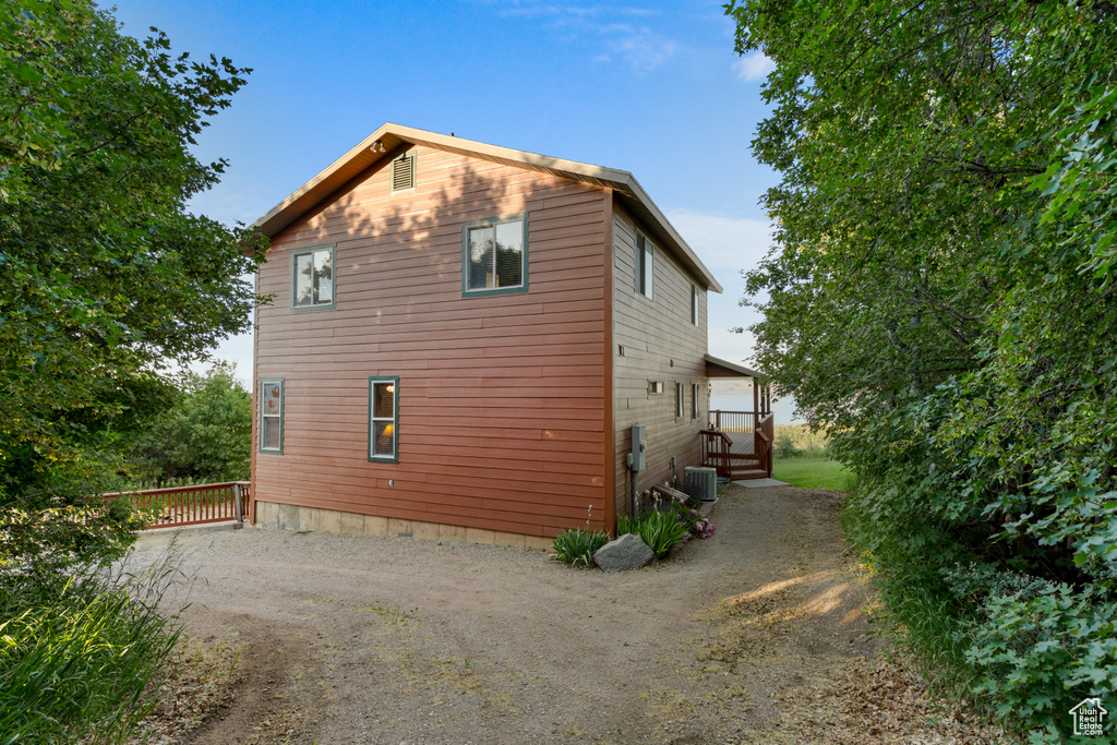 View of property exterior featuring dirt driveway and a central air condition unit