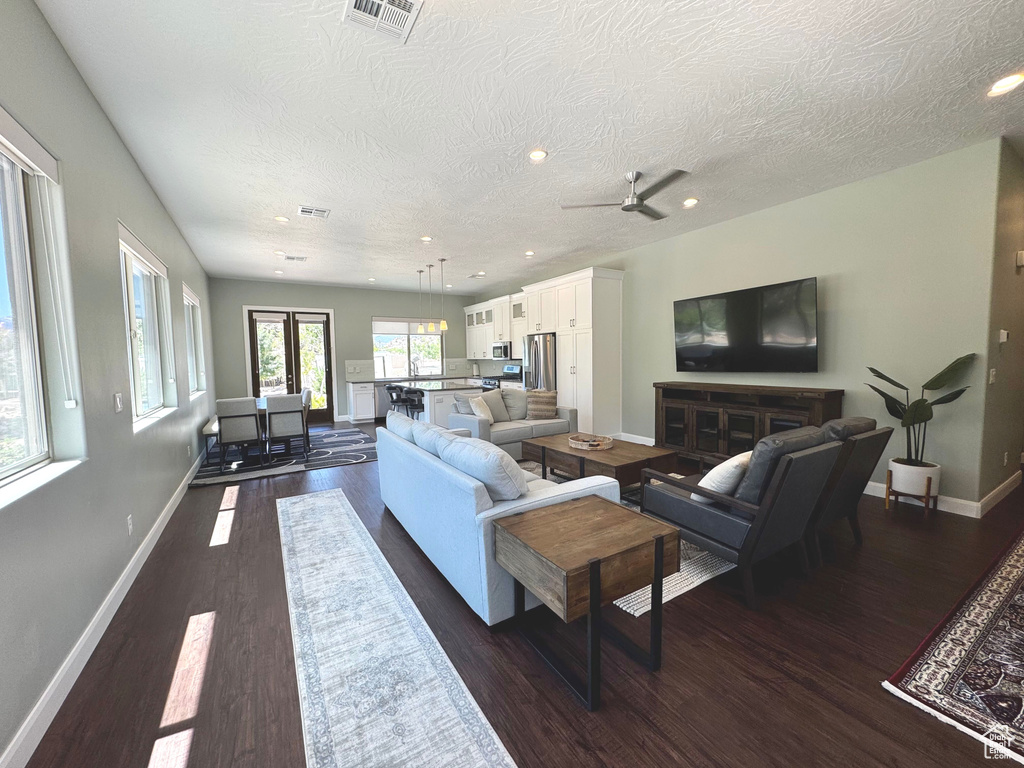 Living room featuring dark wood-style floors, ceiling fan, recessed lighting, and a textured ceiling
