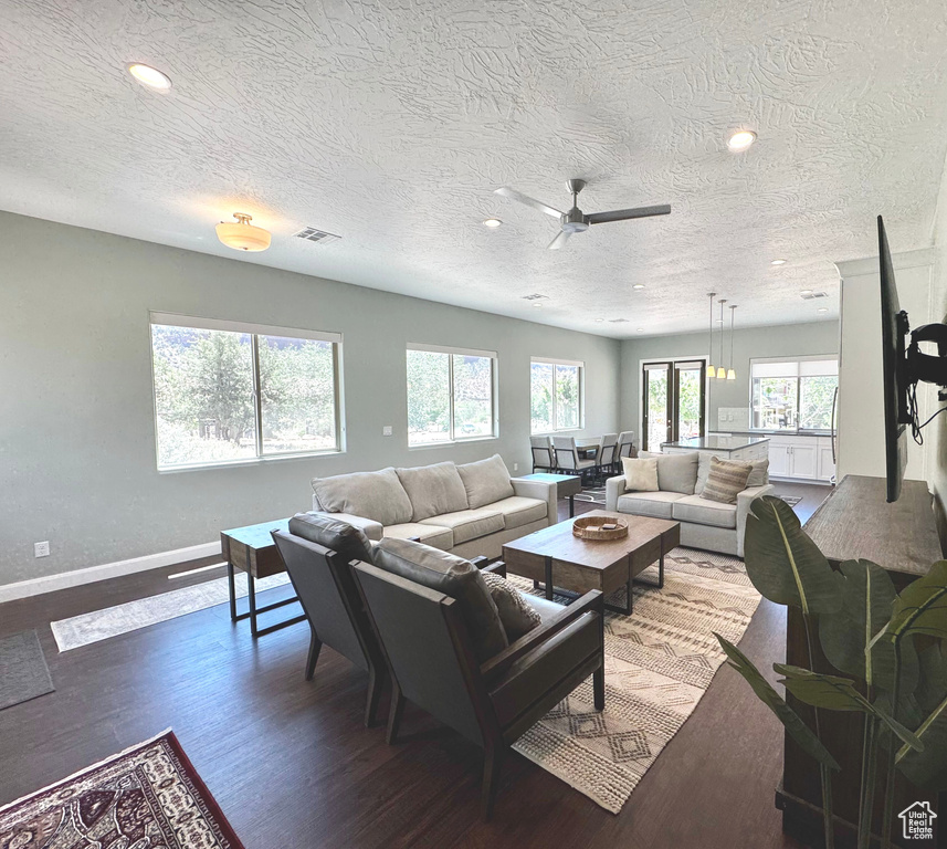 Living area with dark wood finished floors, a textured ceiling, ceiling fan, and recessed lighting