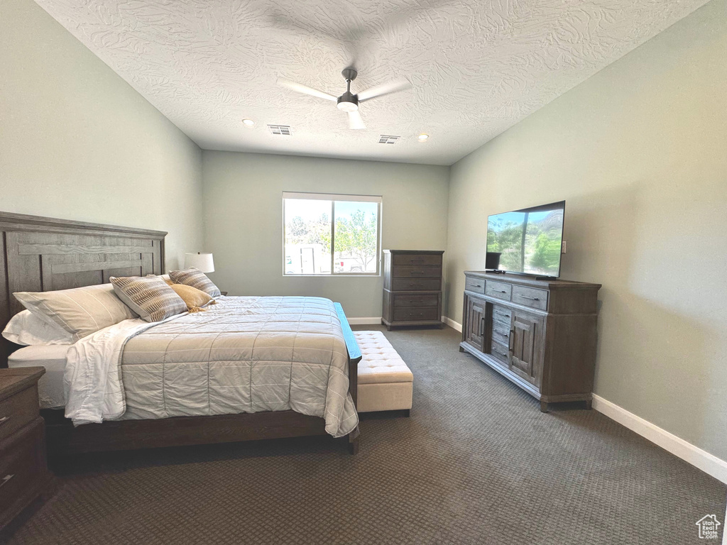 Carpeted bedroom with a textured ceiling, ceiling fan, and recessed lighting