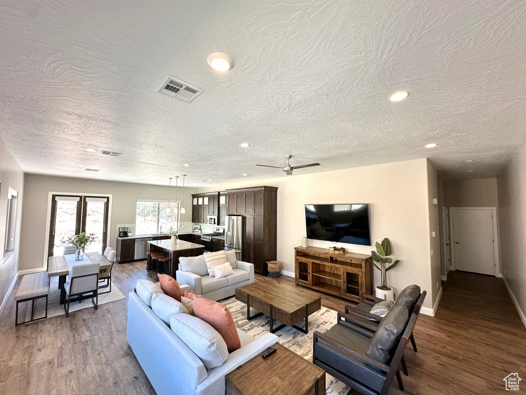 Living area with wood finished floors, recessed lighting, and a textured ceiling