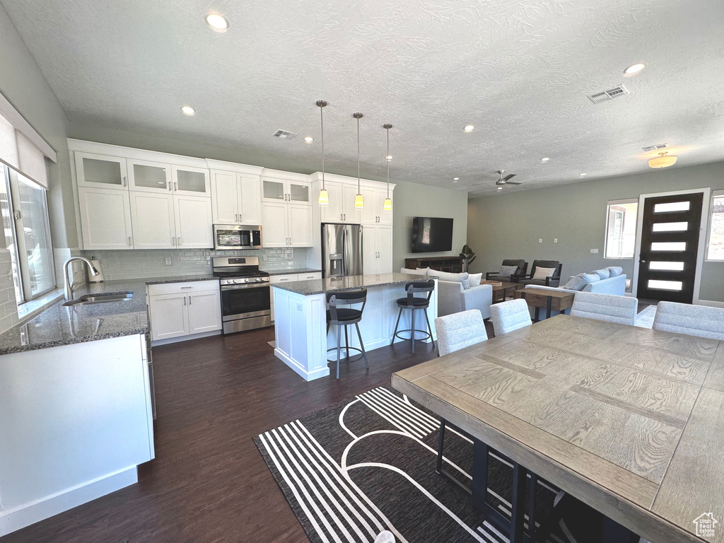 Kitchen with appliances with stainless steel finishes, a center island, dark wood-style flooring, recessed lighting, and decorative backsplash