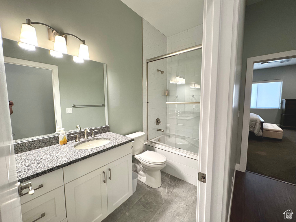 Full bathroom with vanity, shower / bath combination with glass door, marble finish floors, and ensuite bathroom
