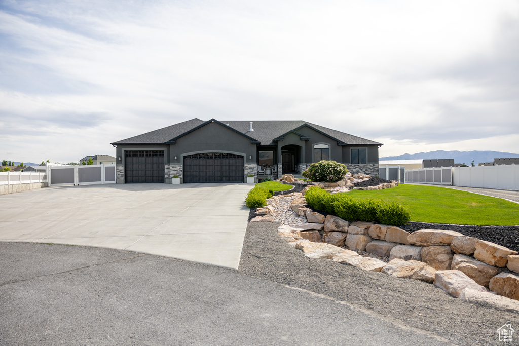 View of front of property with a garage, stone siding, concrete driveway, and stucco siding